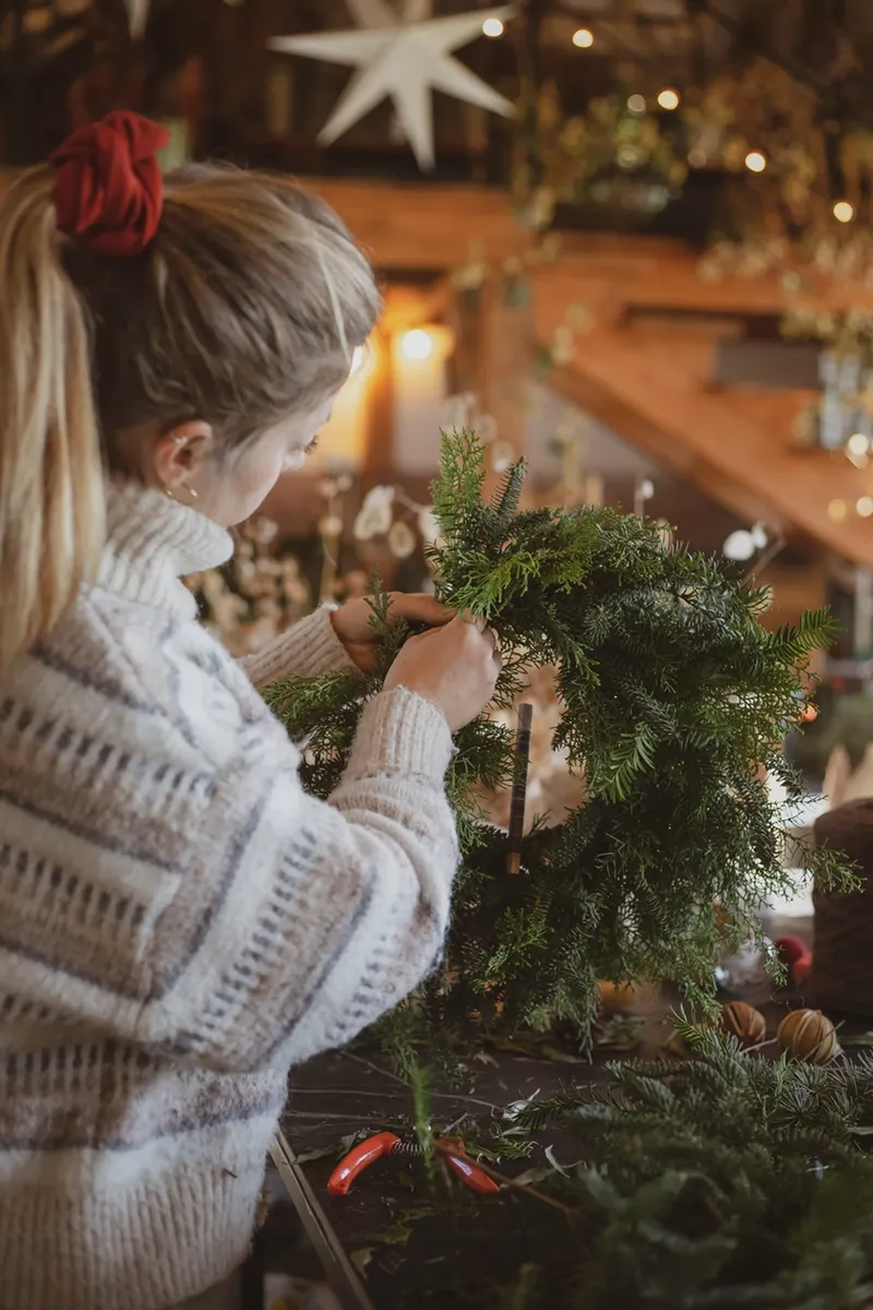 Silvia Micheli intreccia ghirlanda di rami verdi durante laboratorio natalizio sostenibile