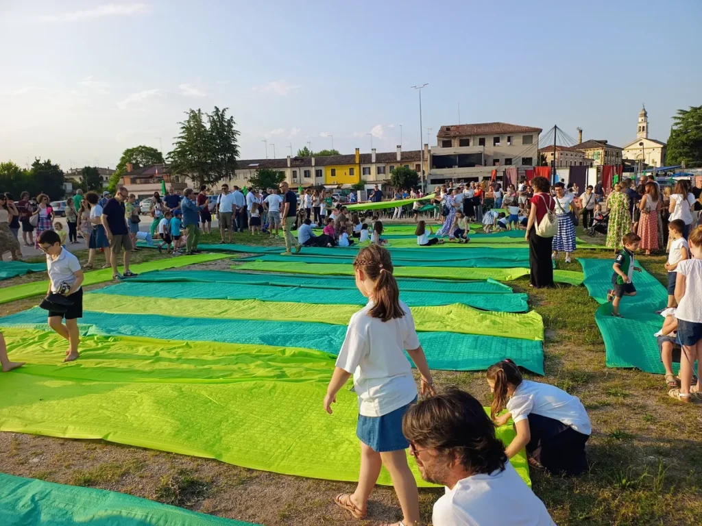 Giornata di comunità al Prato della Fiera Famiglie e bambini su teli colorati all’aperto.